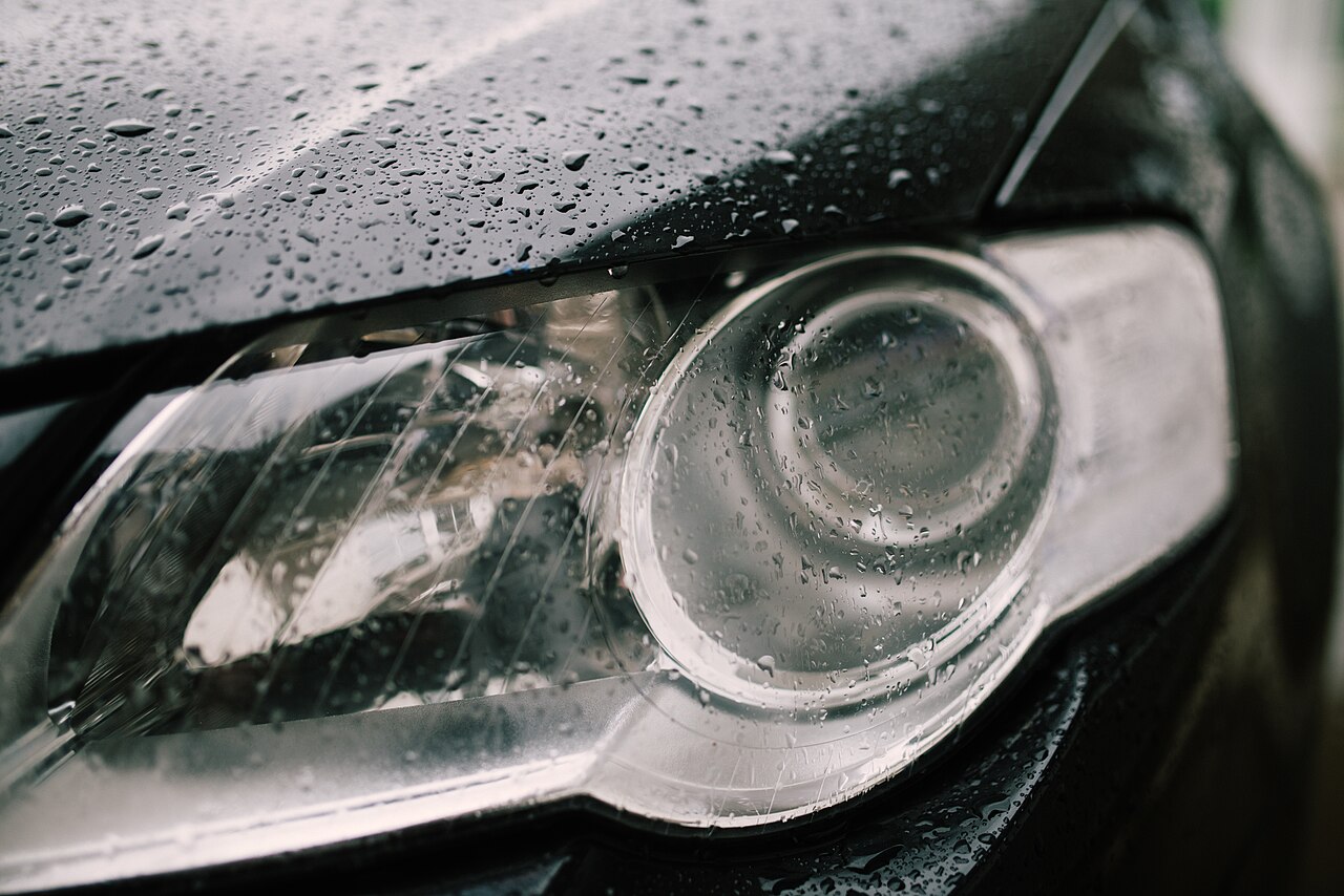 Close-up of a car headlamp covered with rain droplets