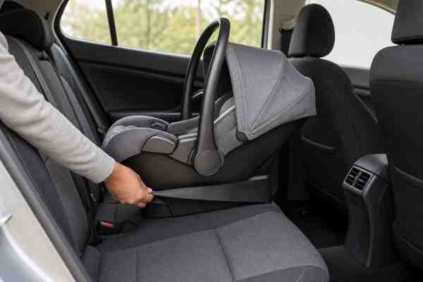 A rear-facing infant car seat being checked in the rear of a car